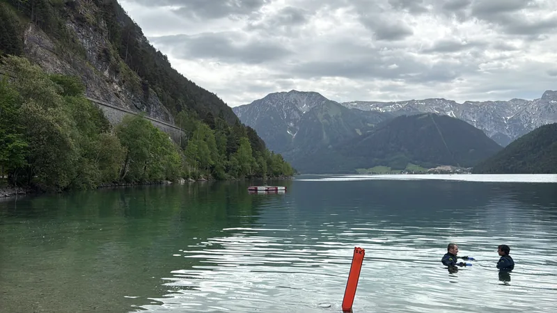 Personen mit Tauchausrüstung im Wasser eines von Bergen eingerahmten Sees.